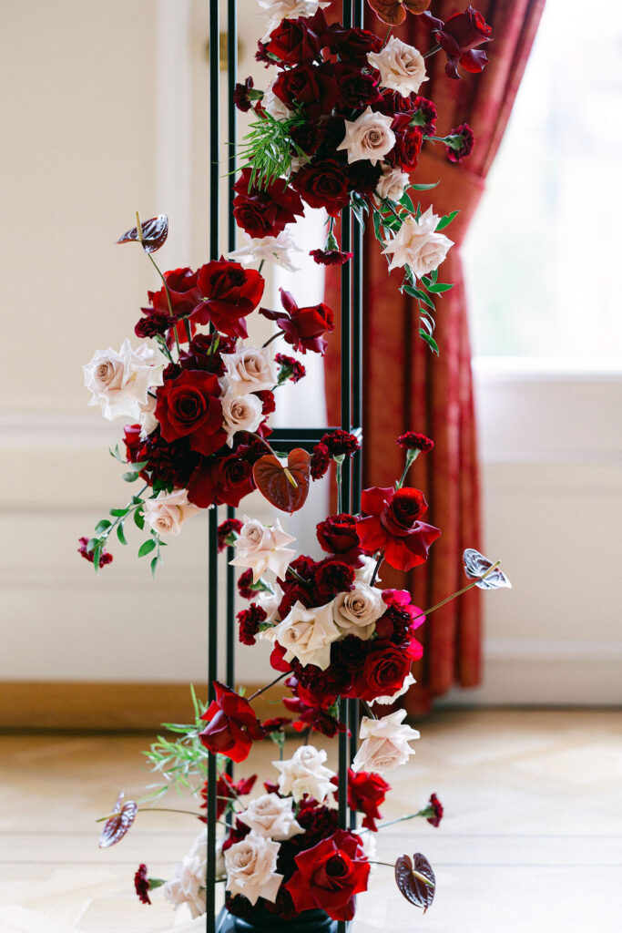 Close-up of a lush wedding floral installation at Cercle Cité featuring deep red roses, blush blooms, anthurium, and trailing greenery designed by Claudia Leinen