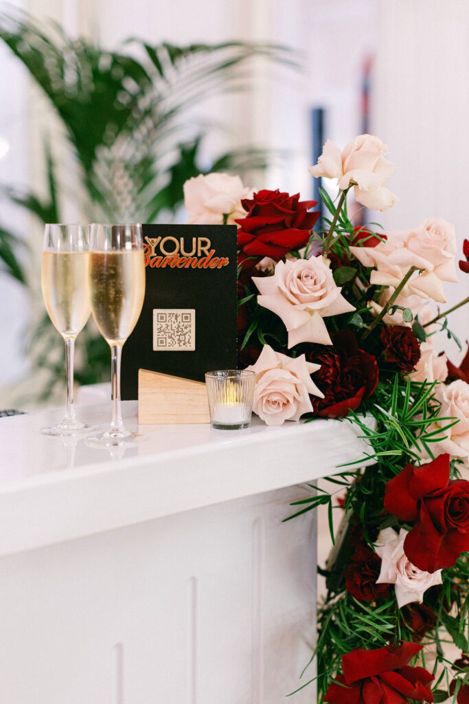 Your Bartender Luxembourg cocktail bar setup with champagne flutes, roses, and branded signage at a Cercle Cité wedding reception