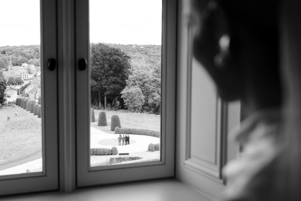 View from a window at Château de Mirwart Belgium looking out over the formal gardens and Belgian Ardennes countryside on a wedding morning