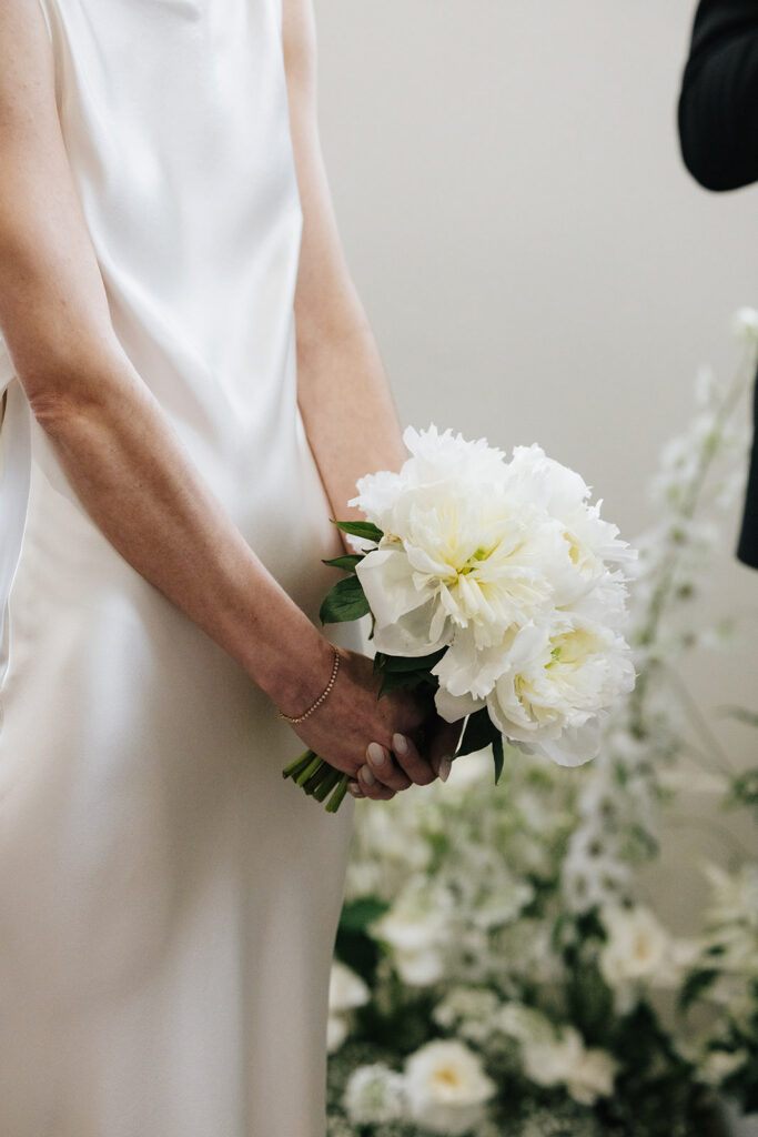 Bride Carla holding a white peony and delphinium bridal bouquet by Catherine Alves at her Château de Mirwart wedding