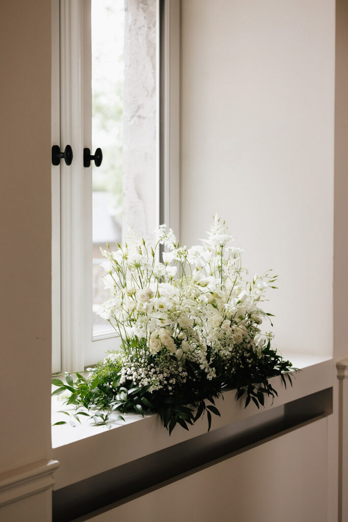 White wedding floral arrangement by Catherine Alves displayed on a windowsill at Château de Mirwart Belgium