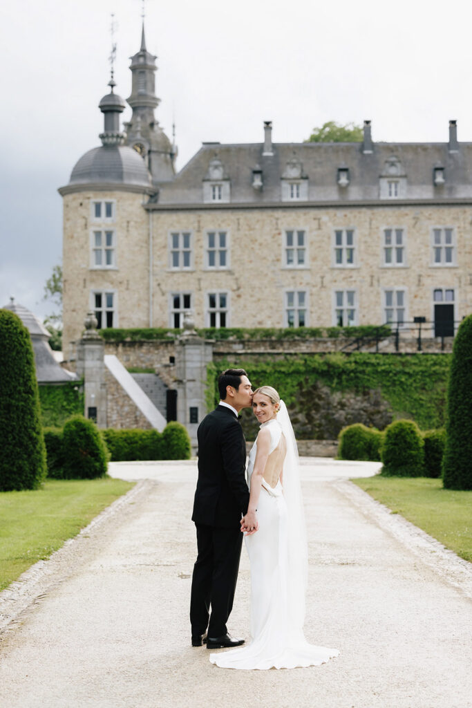 Carla and Robin wedding portrait standing together on the formal garden path at Château de Mirwart Belgium with the château facade behind them