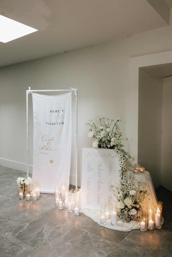 Wedding seating chart display at Château de Mirwart Belgium with acrylic frame white banner name ribbons by Medusa surrounded by candles and white florals