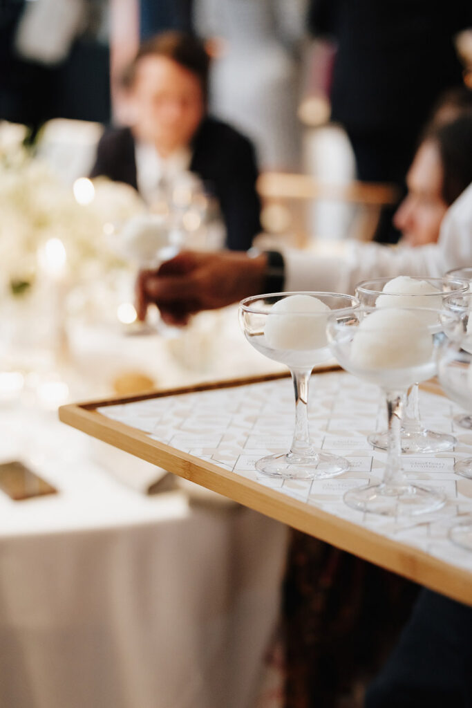 Wedding reception guests at Château de Mirwart Belgium with soft candlelight white florals and coupe glasses on the table