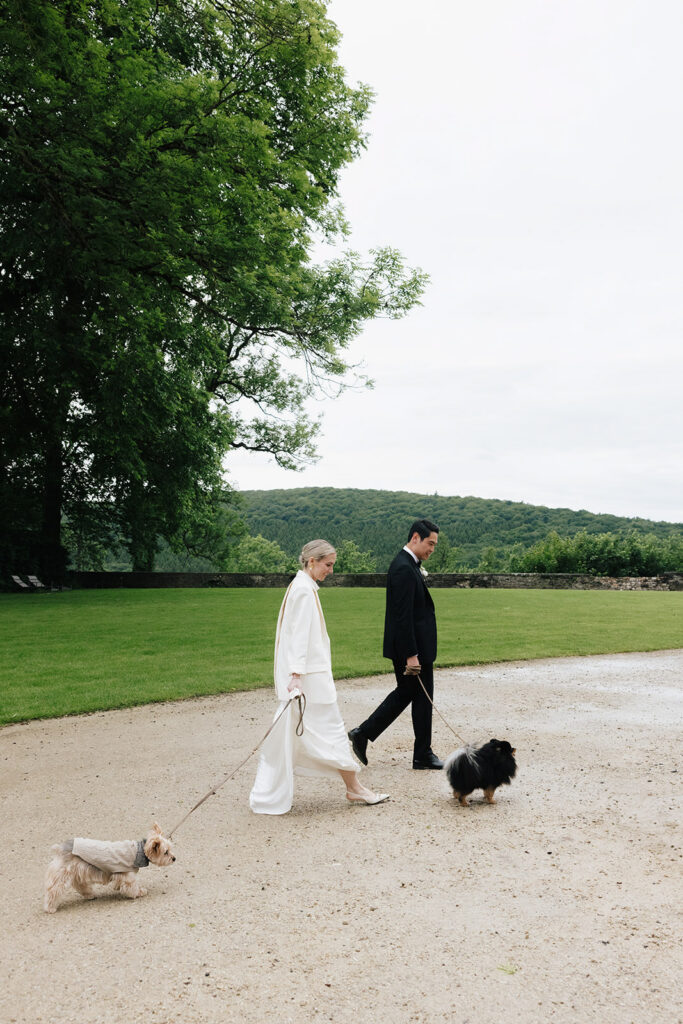 Carla and Robin walking their dogs on the grounds of Château de Mirwart Belgium after their wedding ceremony in the Belgian Ardennes
