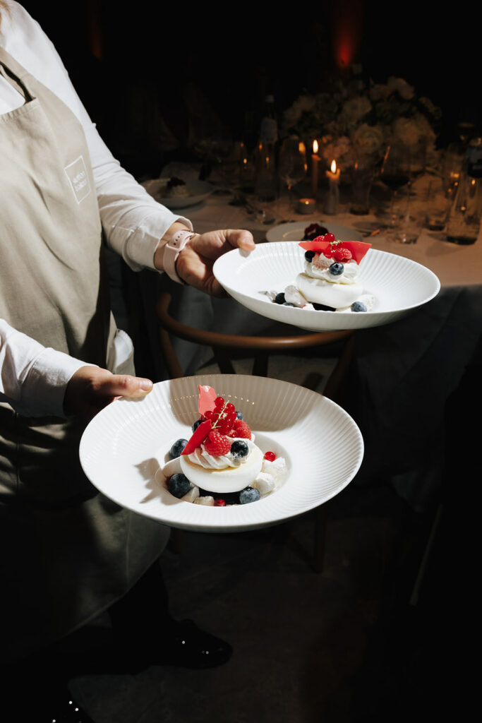 Steffen Traiteur wedding dessert being served at Château de Mirwart Belgium with berry pavlova on white plates by candlelight