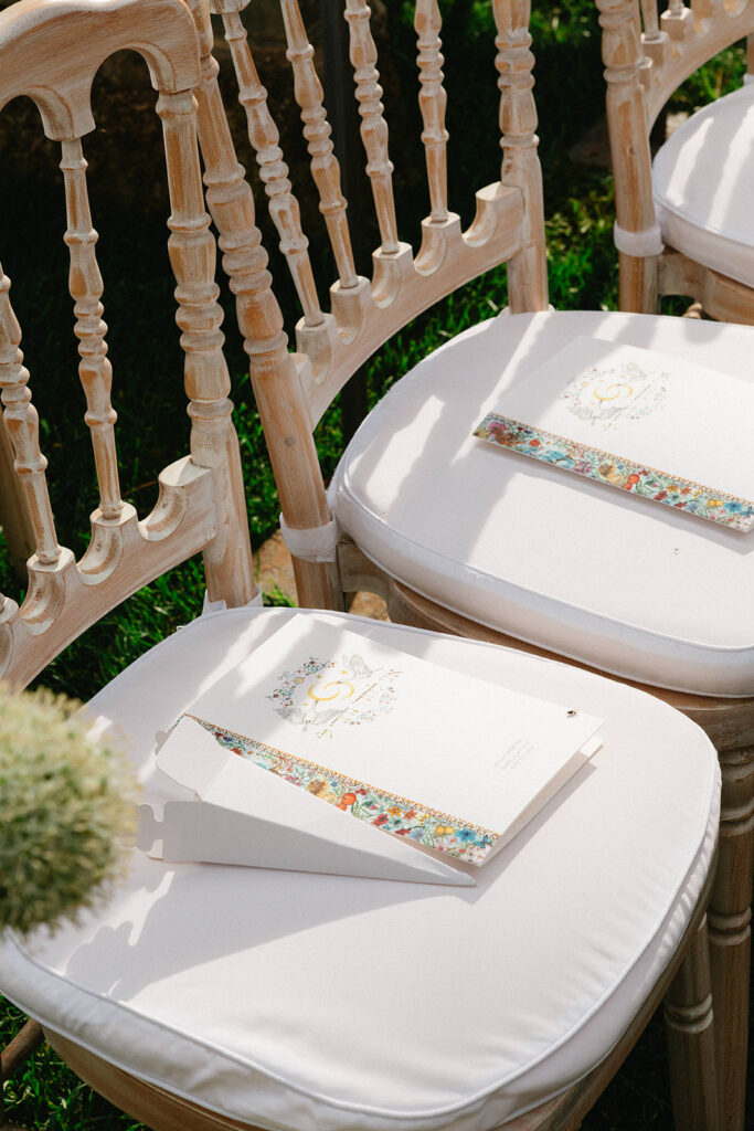 Hand painted wedding ceremony program designed by the bride resting on a guest chair at Villa Cimbrone Ravello Italy