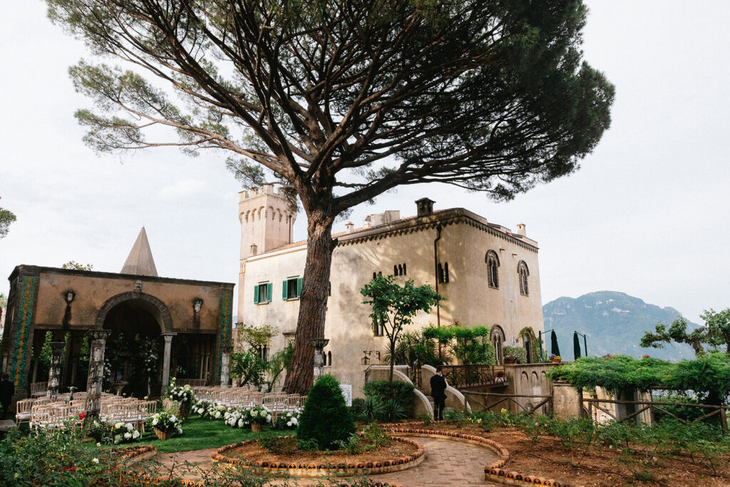 Villa Cimbrone gardens set for a wedding ceremony in Ravello Italy with white floral arrangements guest seating and the historic villa in the background