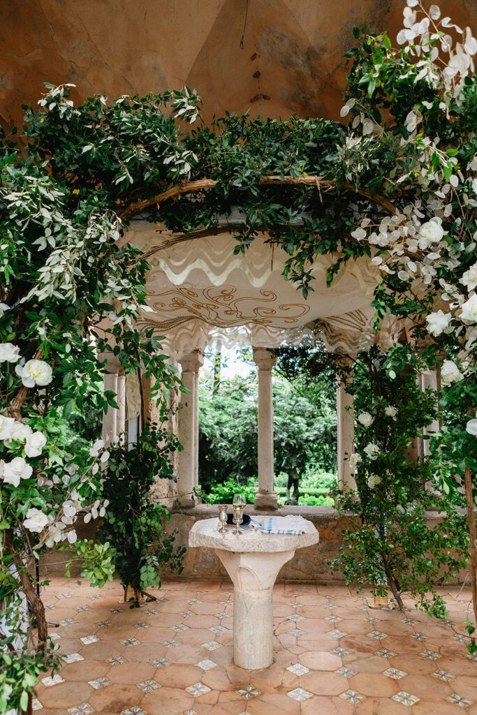 Jewish wedding chuppah decorated with lush greenery and white florals inside the historic loggia at Villa Cimbrone Ravello Italy