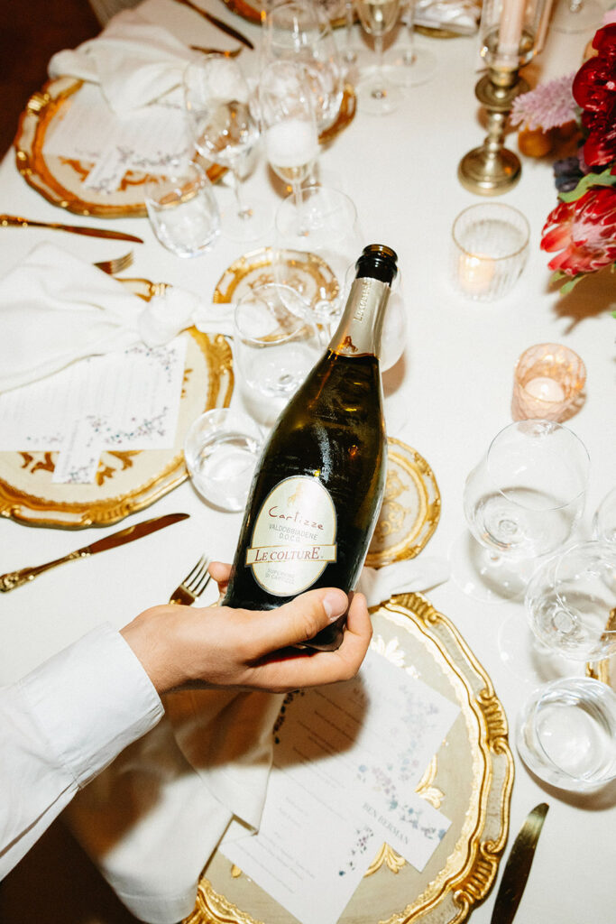 Waiter pouring champagne at a wedding reception table set with gold rimmed china and crystal glassware at Villa Cimbrone Ravello Italy