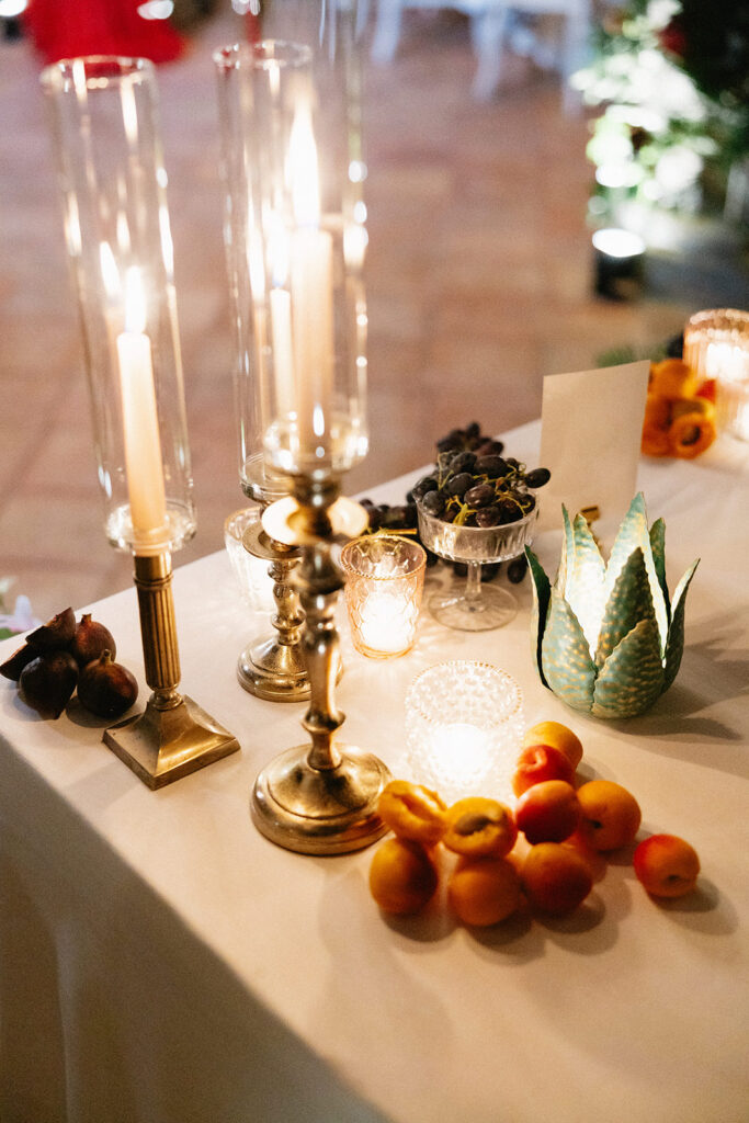Wedding reception tablescape detail at Villa Cimbrone crypt with brass candlesticks taper candles fresh peaches and artichoke centerpiece accents