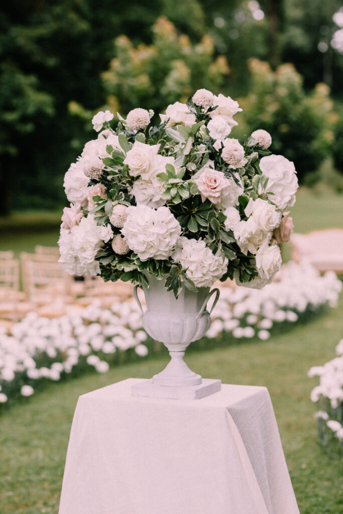 White hydrangea and rose floral urn arrangement by Claudia Leinen at the outdoor wedding ceremony at Château du Bois d'Arlon Belgium