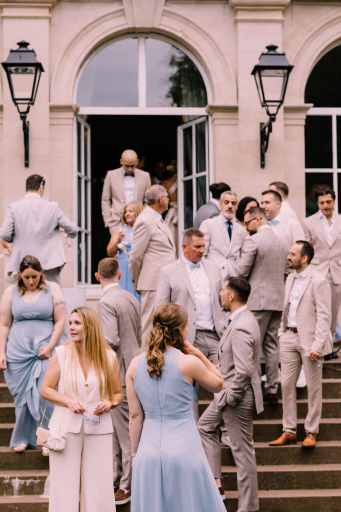 Wedding guests mingling on the grand steps of Château du Bois d'Arlon Belgium during the cocktail hour