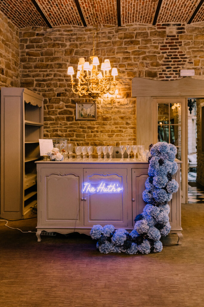 Custom neon bar sign reading The Hutkin at Château du Bois d'Arlon Belgium decorated with blue hydrangea floral installation