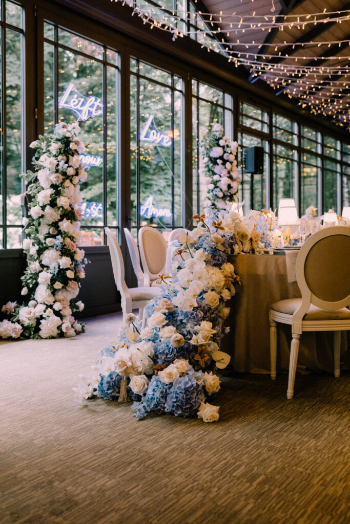 Sweetheart table setup at Château du Bois d'Arlon Belgium with blue and white hydrangea floral arrangements neon love signs and fairy lights