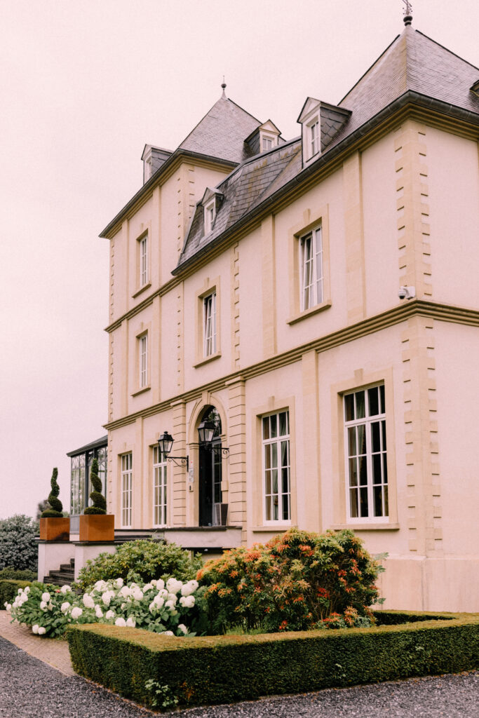 Château du Bois d'Arlon exterior facade with manicured garden hedges and seasonal flowers in Arlon Belgium