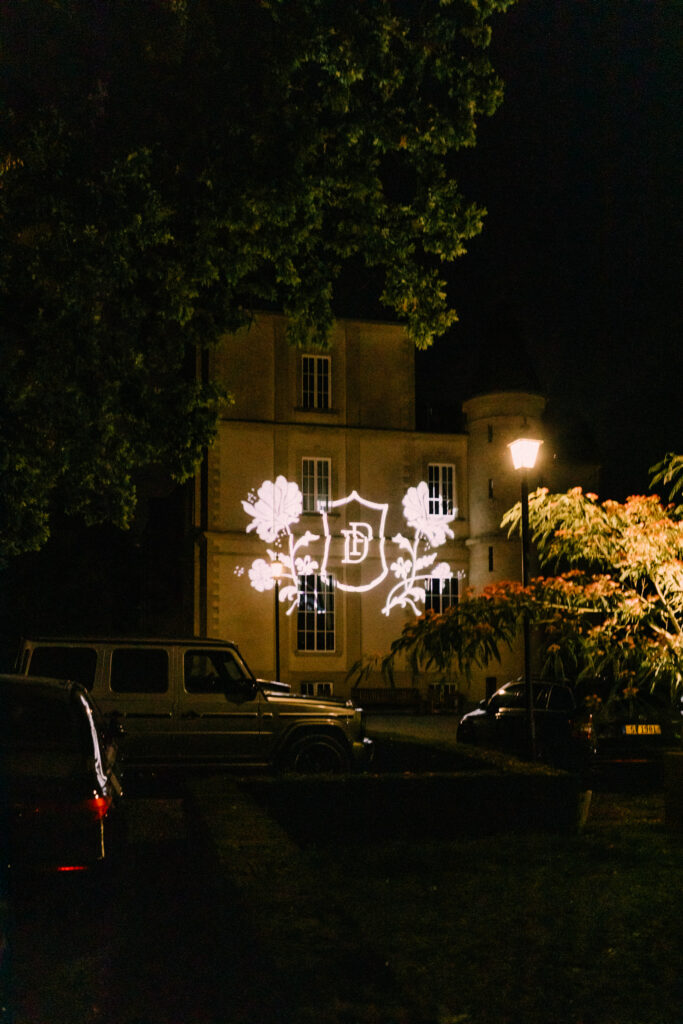 Custom couple logo projected onto the facade of Château du Bois d'Arlon Belgium at night as guests departed their luxury wedding